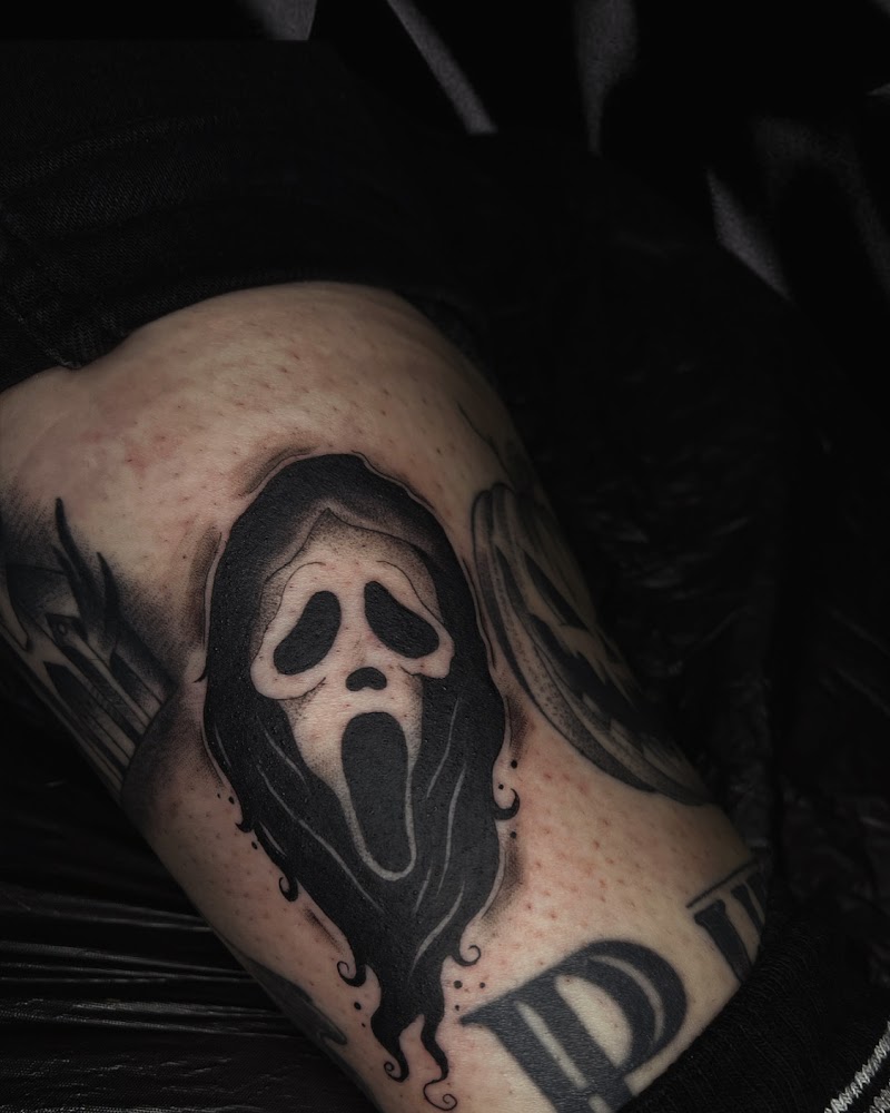Blackwork Ghostface masker tattoo op de bovenarm.