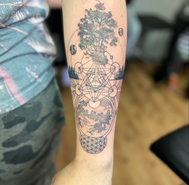 Geometrische dotwork tattoo met boom, planeten en heilige geometrie op onderarm.