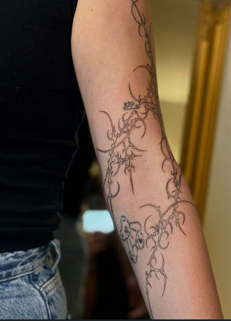 Fineline abstracte doornen en organische vormen op de onderarm.