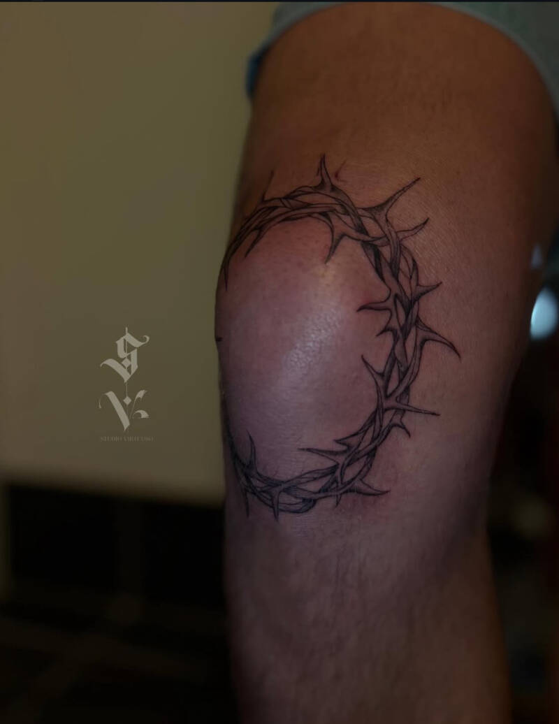Gedetailleerde doornenkroon tattoo rondom de knie.