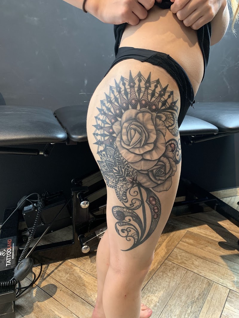 Grote zwart-wit tattoo van rozen en mandala op bovenbeen.