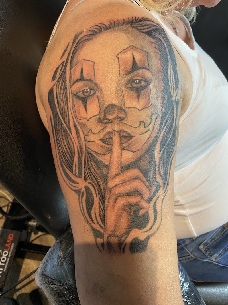 Zwart-wit portret van een vrouw met clownsmake-up en een vinger voor haar mond.