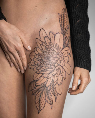 Grote fineline bloem tattoo op het bovenbeen.