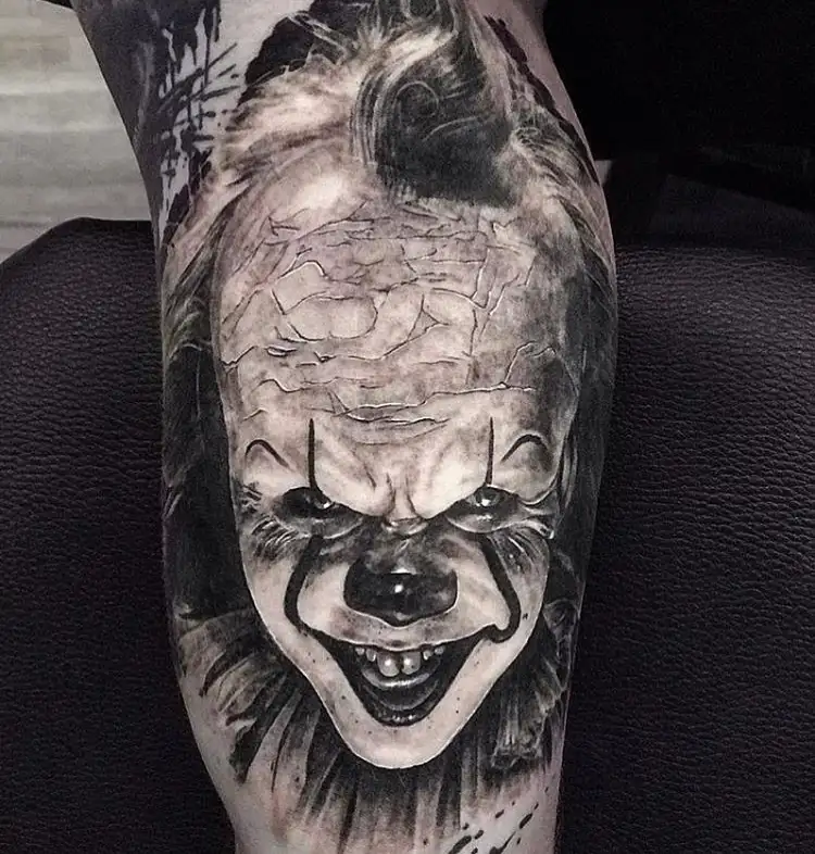 Realistische zwart-wit tattoo van Pennywise de clown op het onderbeen.