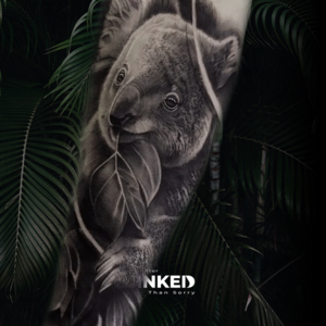 Realistische zwart-wit tattoo van een koala met een blad op de bovenarm.