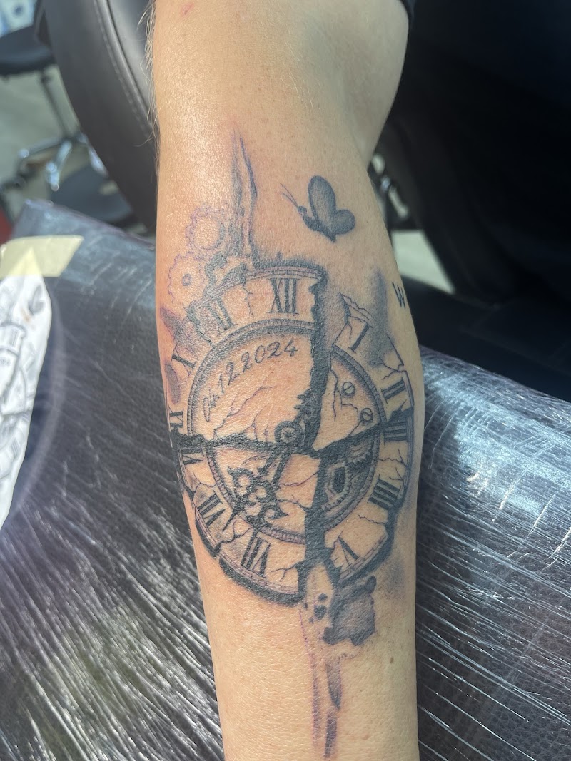 Gebroken klok met datum 04.12.2024 en vlinder op onderbeen.