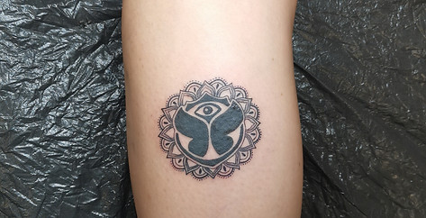 Blackwork Tomorrowland logo in een mandala op het onderbeen.