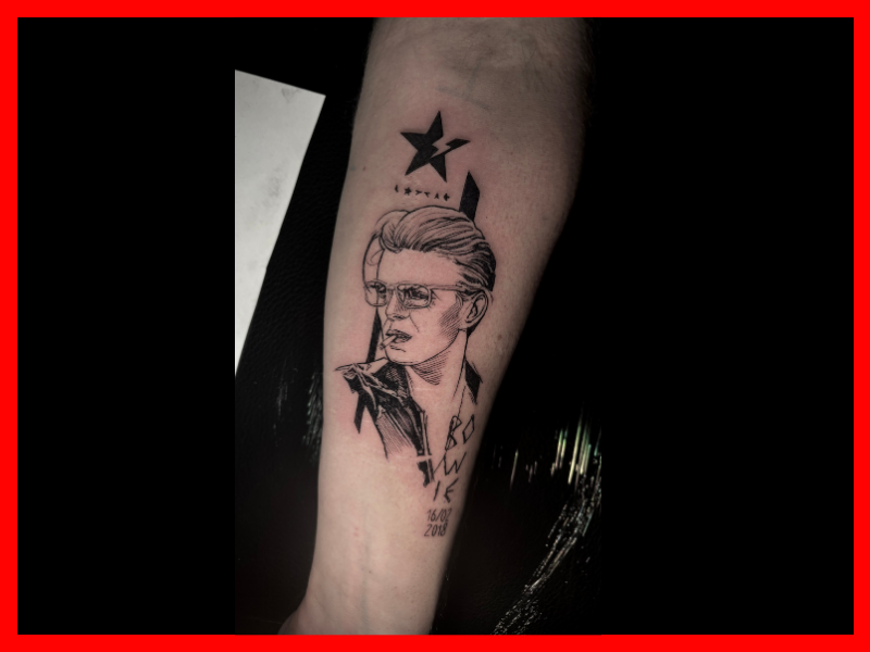 Blackwork portret van David Bowie met ster en tekst op onderarm.