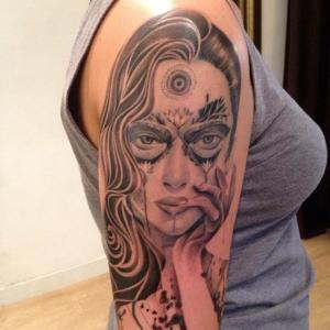 Blackwork portret van een vrouw met een derde oog en masker op de bovenarm.