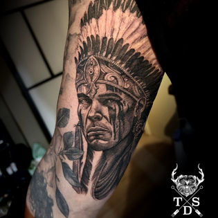 Realistisch portret van een inheemse man met verentooi op de bovenarm.