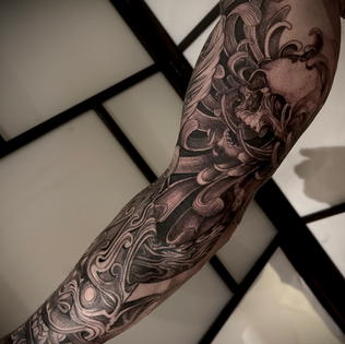 Zwart-wit schedel en chrysant tattoo in Japanse stijl op een arm.