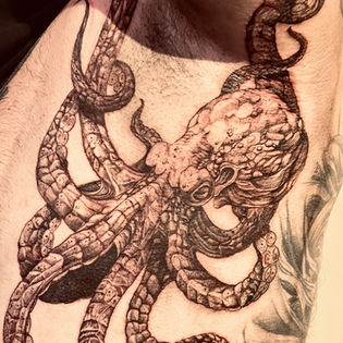 Gedetailleerde zwart-wit inktvis tattoo op de schouder.