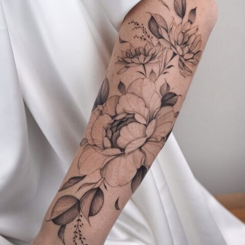 Grote fineline bloemen tattoo op onderarm met dotwork shading.