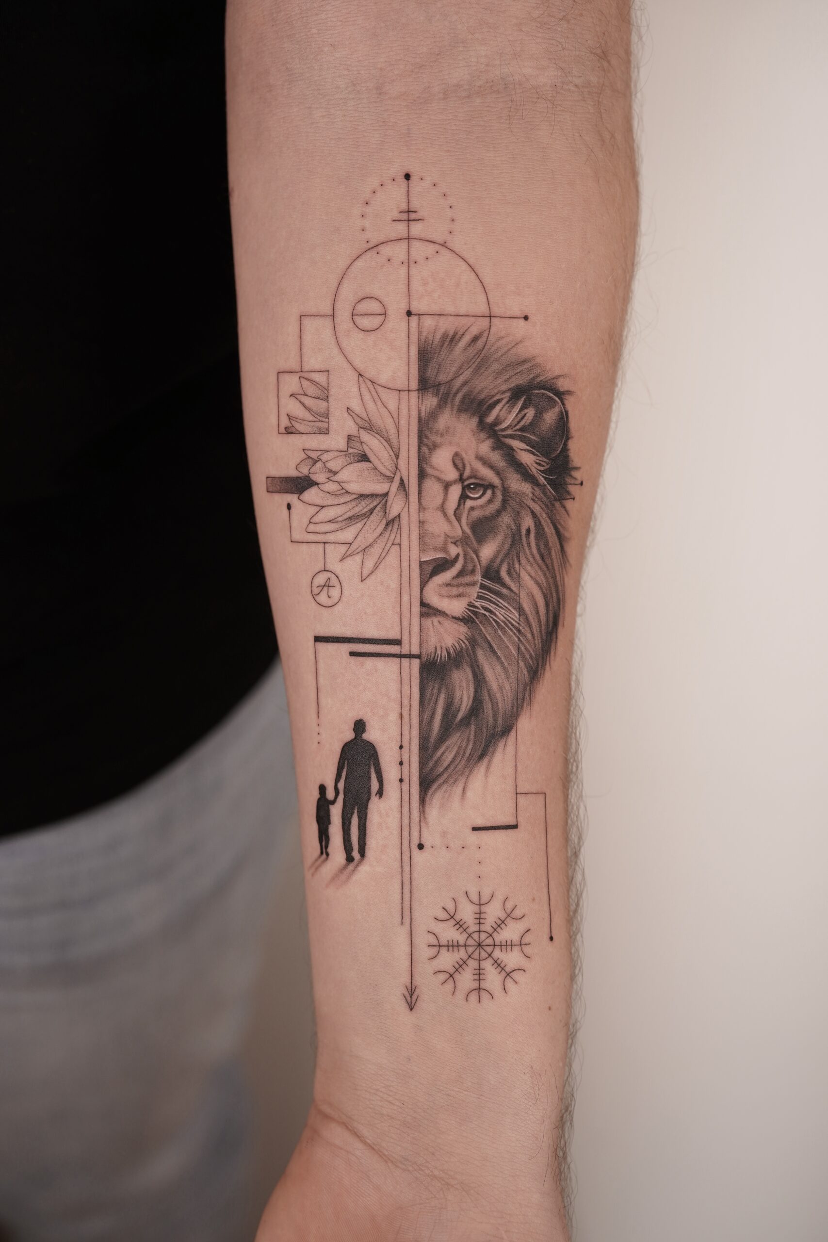 Geometrische leeuw, lotus, vader en kind, en vegvisir op onderarm.