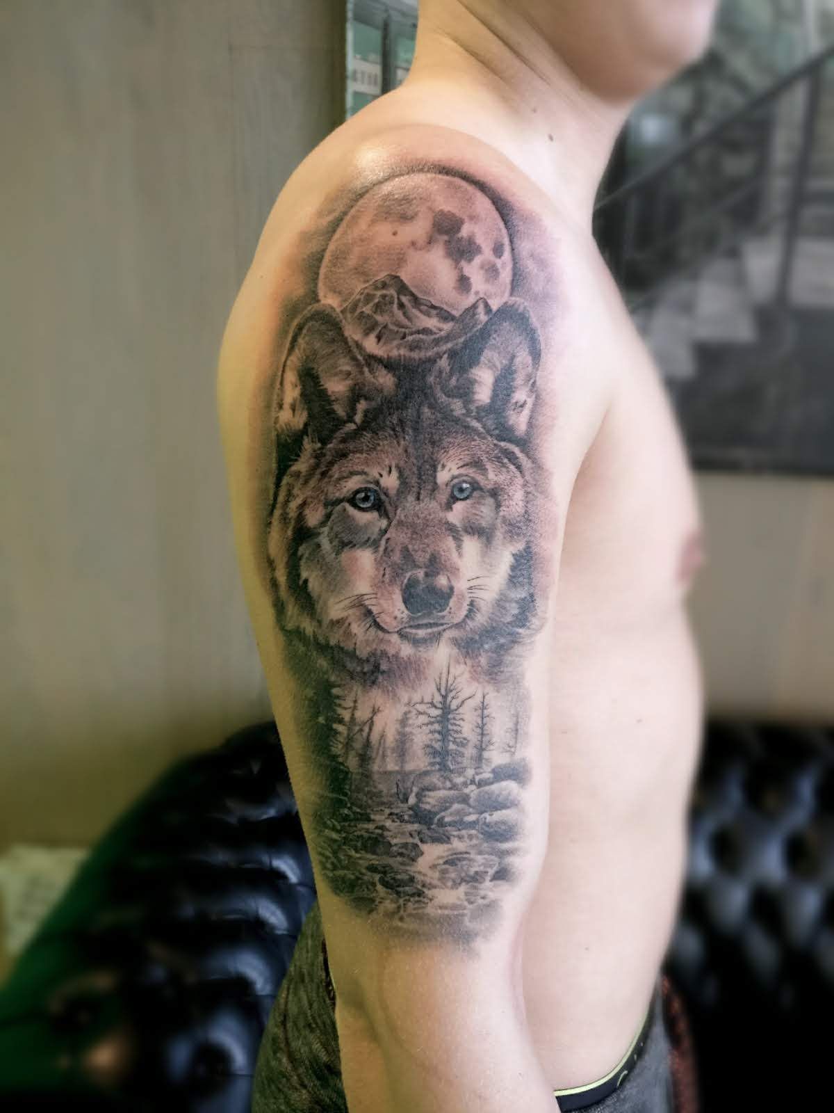 Realistische wolf met maan en boslandschap op bovenarm.