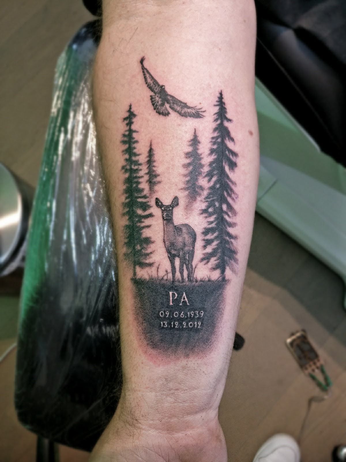 Blackwork tattoo van een hert en adelaar in een bos met 'PA' en datums.