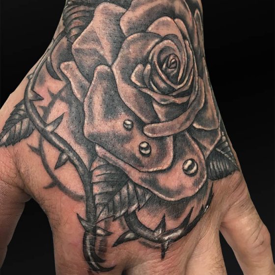 Zwart-wit roos met doornen en waterdruppels op hand.