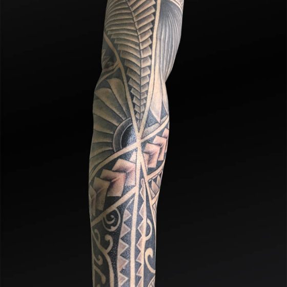 Gedetailleerde Polynesische sleeve tattoo op een arm.