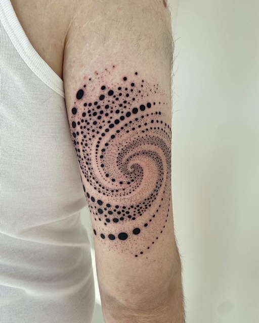 Dotwork spiraal van stippen op de bovenarm.