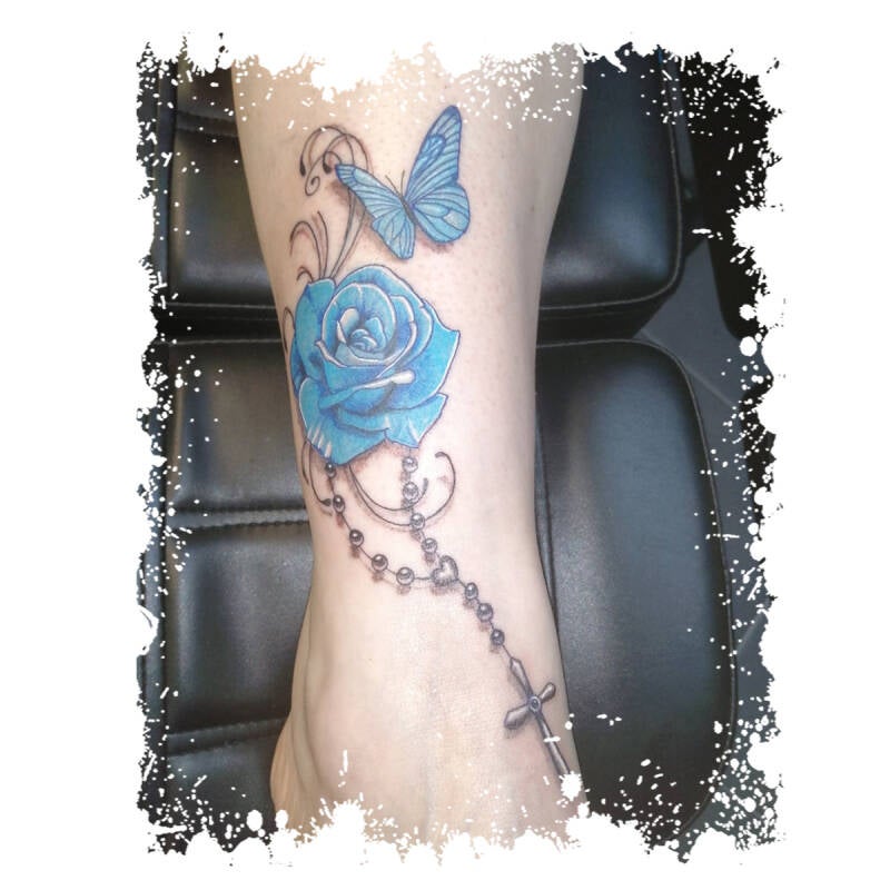 Blauwe roos, vlinder en rozenkrans op enkel.