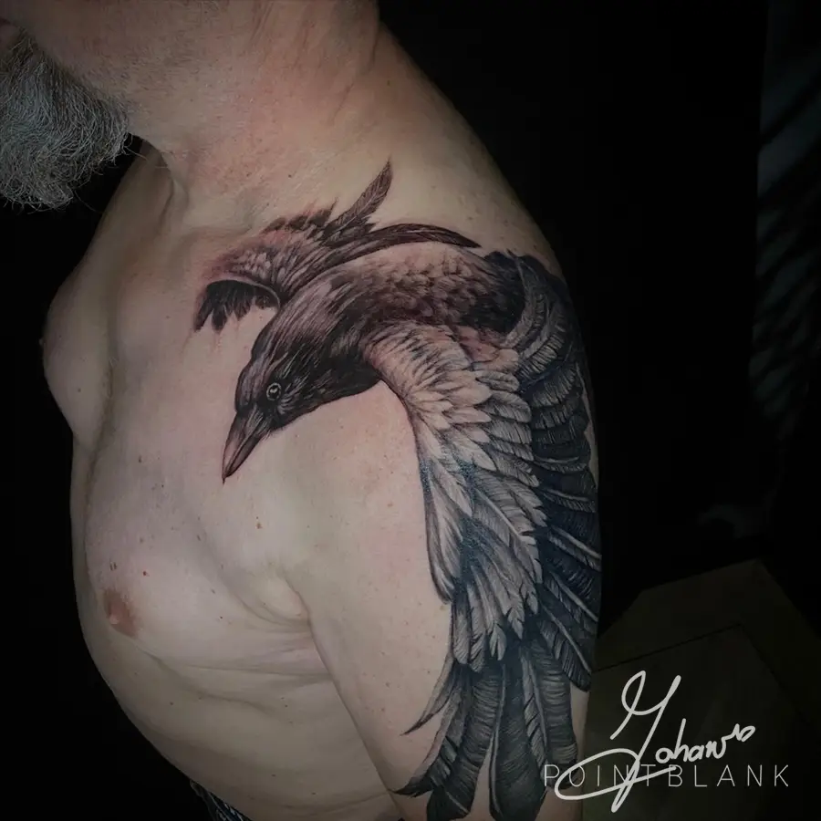 Grote realistische raaf in vlucht op schouder en bovenarm.