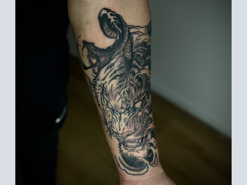 Tijgerkop met slang uit bek en Japanse golven op onderarm.