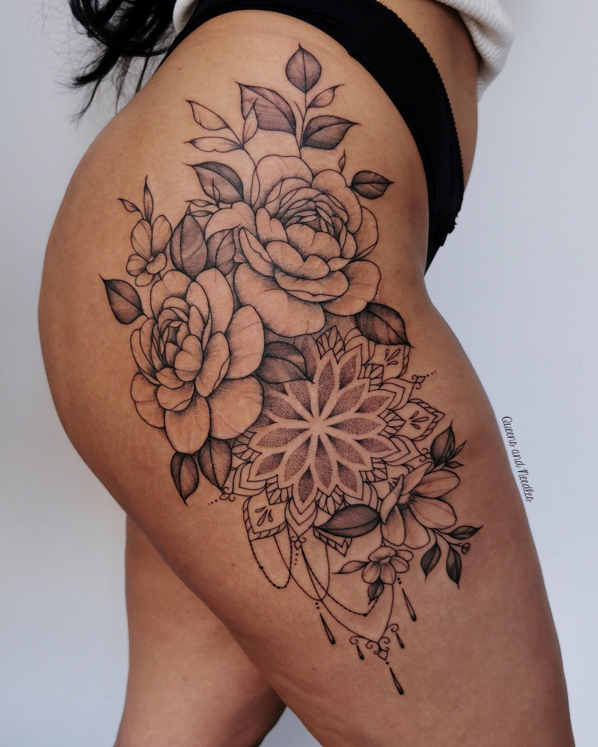 Grote fineline tattoo van rozen, bloemen en een mandala op de heup.
