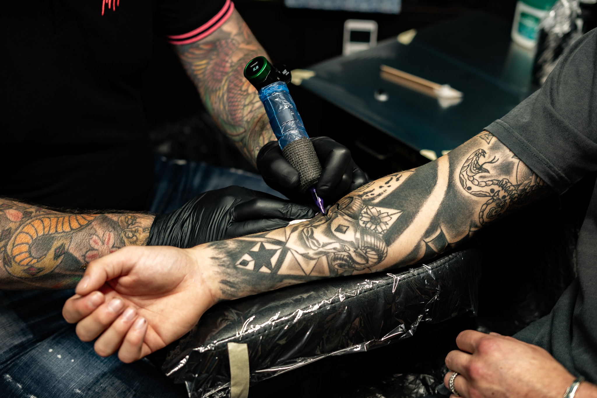 Zwart-wit tattoo in wording op onderarm, met geometrische en schedel elementen.