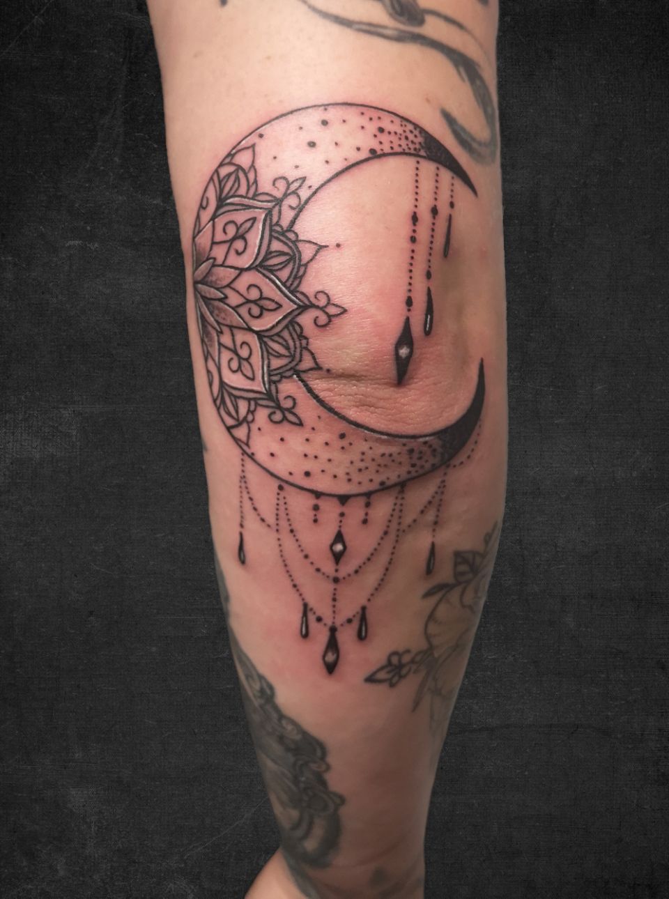 Halve maan met mandala patroon en hangende sieraden op de elleboog.