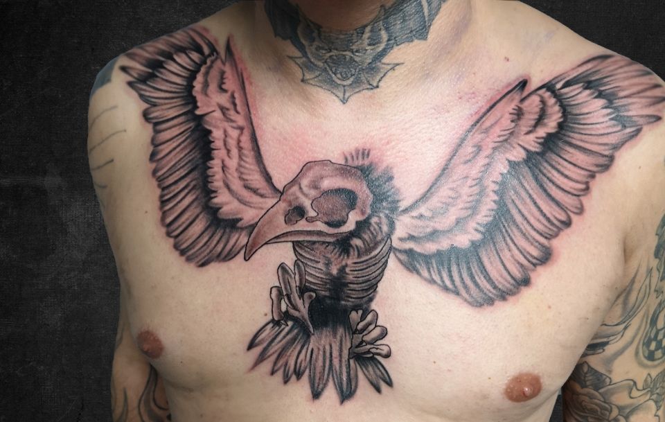 Zwart-witte vogelschedel met vleugels op borst.