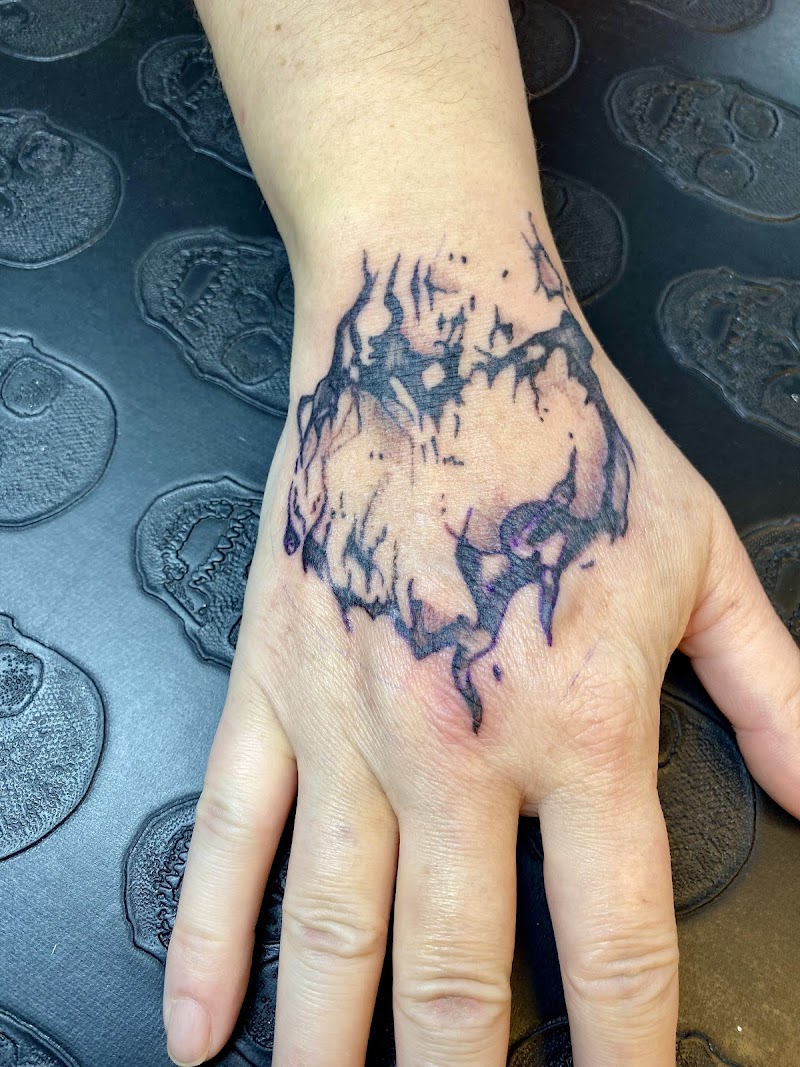 Abstracte, donkere tattoo op de bovenkant van een hand.