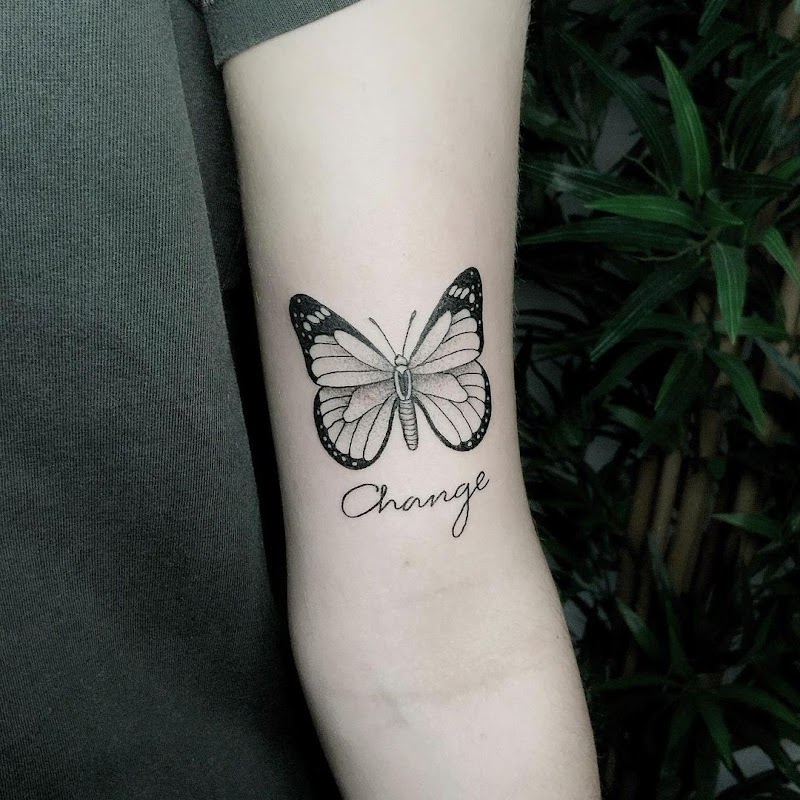 Zwart-wit vlinder met het woord 'Change' eronder op de bovenarm.
