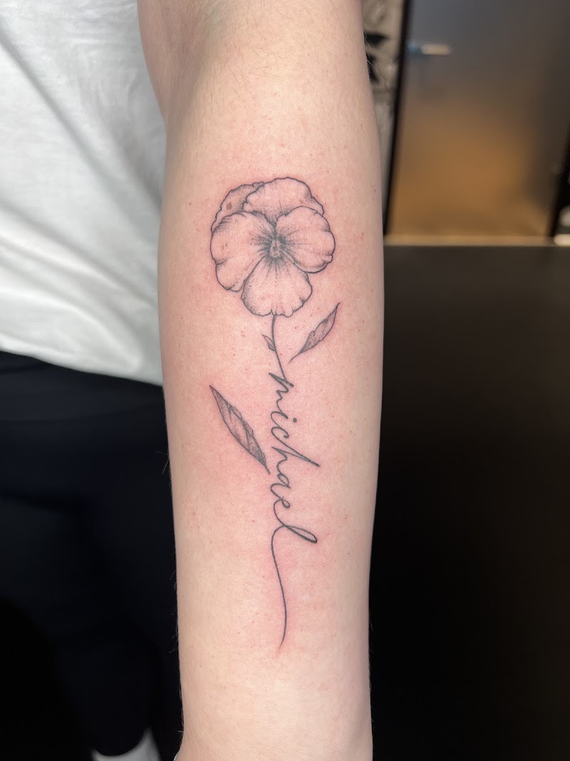 Fineline viooltje met naam 'michael' als steel op onderarm.