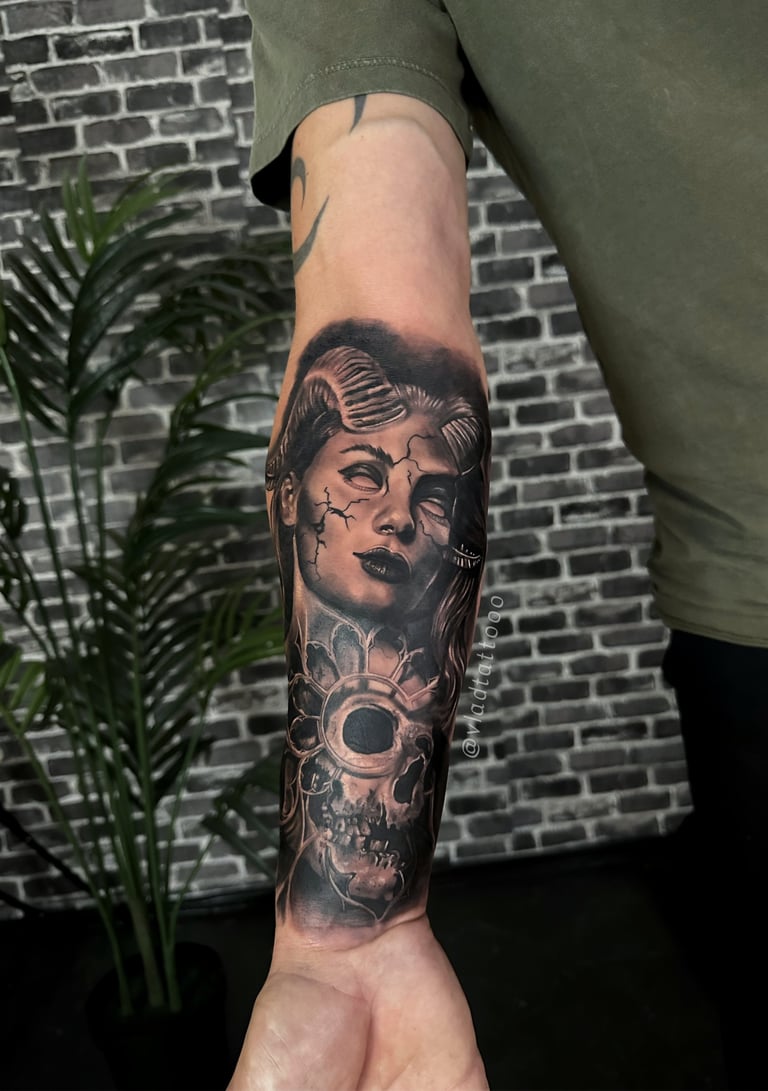 Realistische tattoo van een vrouw met hoorns en een schedel op de onderarm.