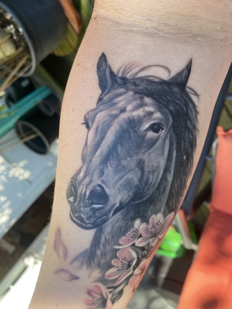 Realistisch paardenhoofd met roze bloesem op onderarm.