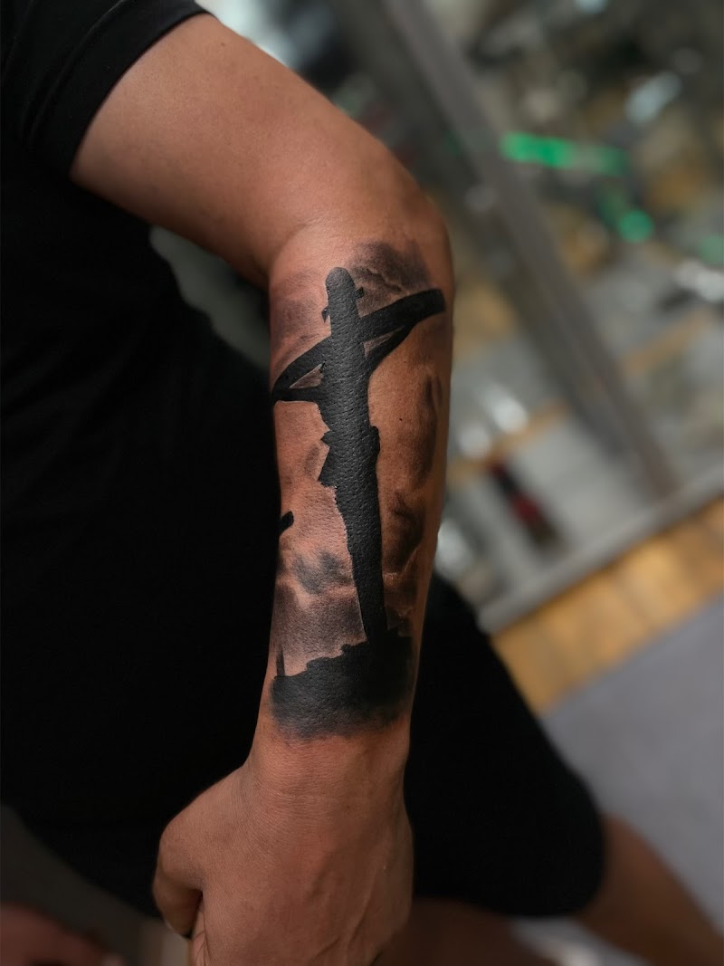 Zwart silhouet van Jezus aan het kruis op de onderarm.