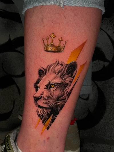 Realistische leeuwenkop met gouden kroon en bliksemschichten op onderbeen.