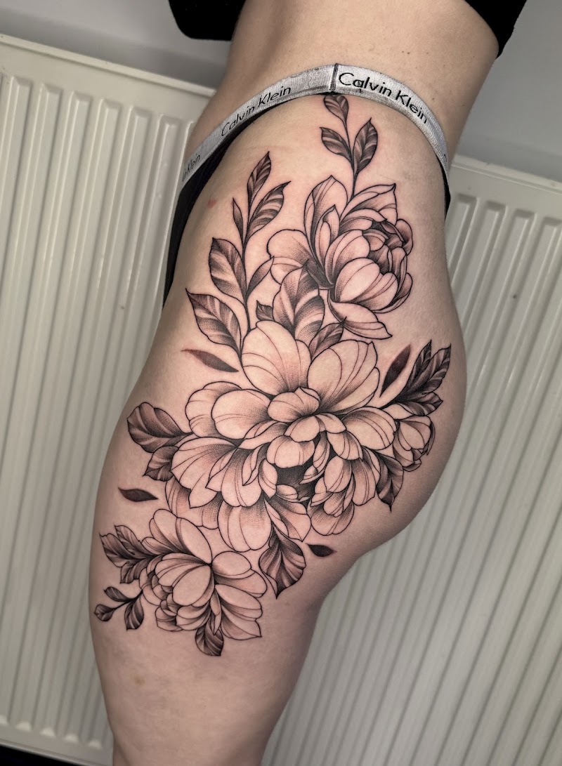 Grote zwart-wit bloemen tattoo op heup en bovenbeen.