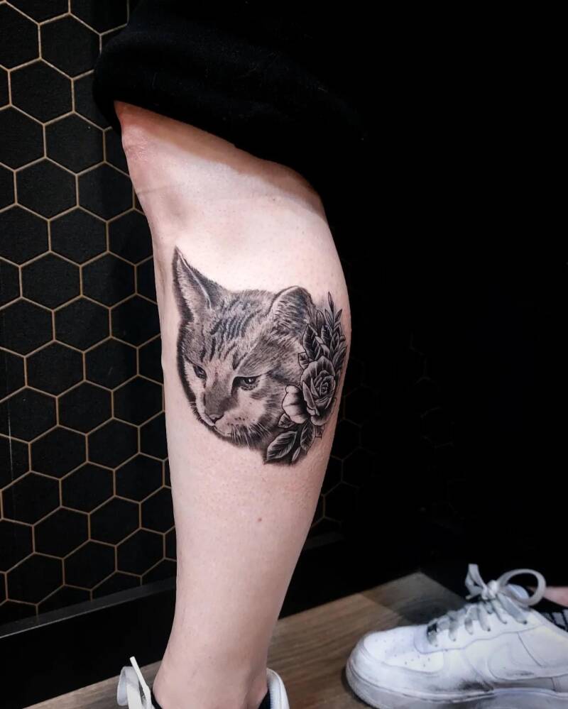 Realistische kattenkop met rozen op het onderbeen.