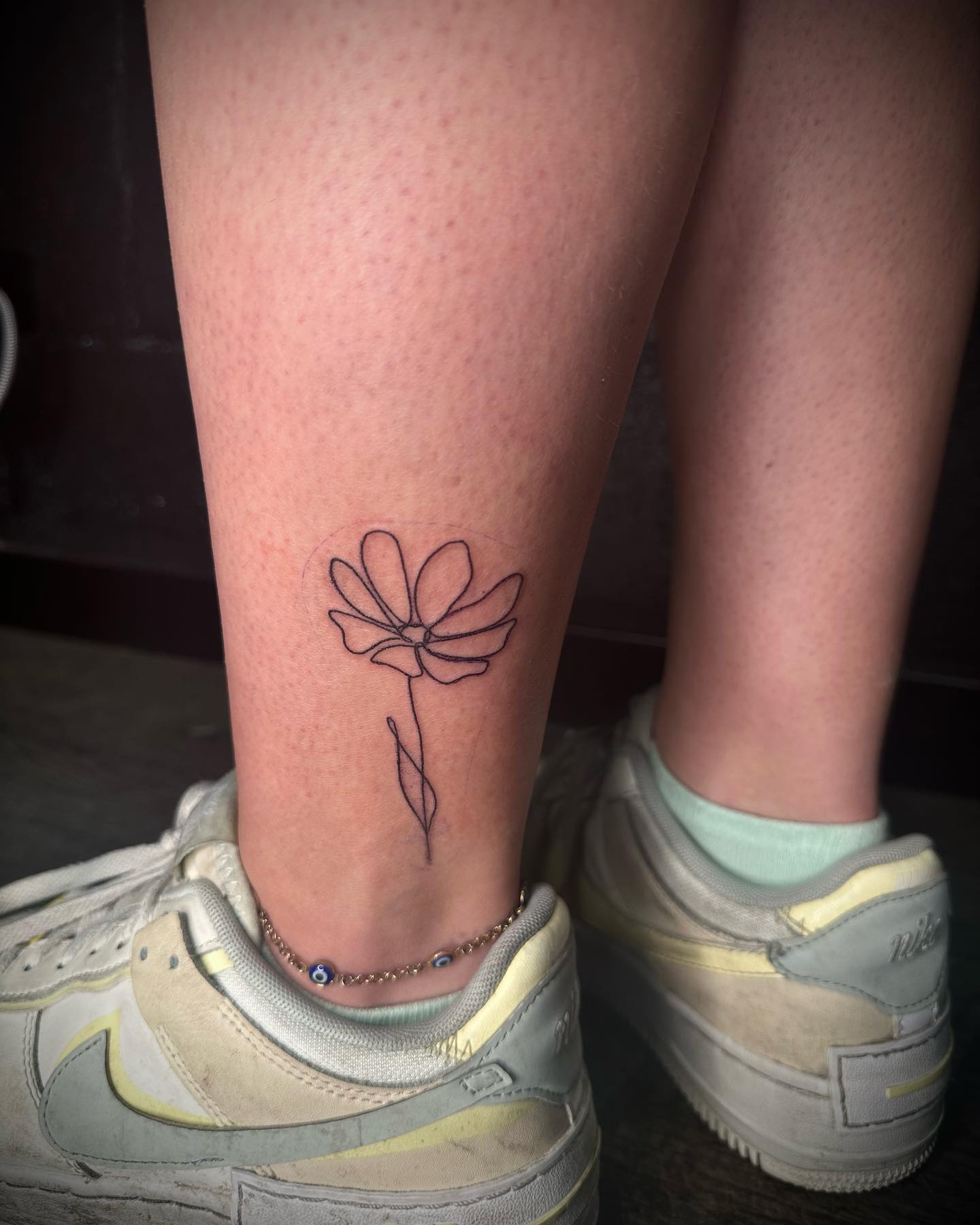 Minimalistische fineline bloem op de enkel.