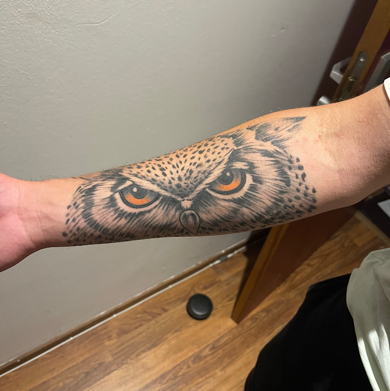 Realistische uil ogen tattoo op onderarm met felle oranje ogen.