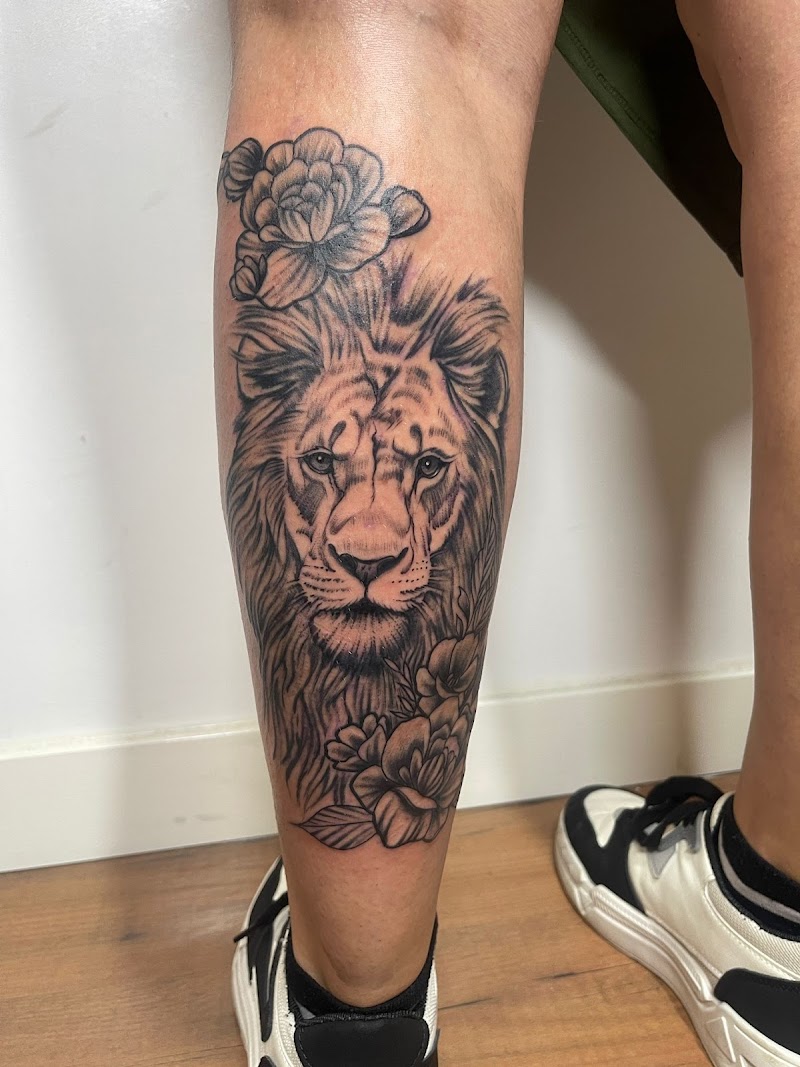 Realistische leeuwenkop met bloemen op onderbeen.