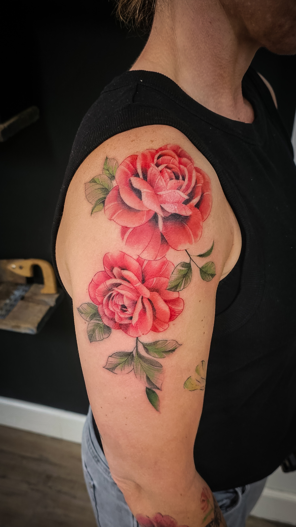 Twee rode rozen met groene bladeren op de bovenarm.