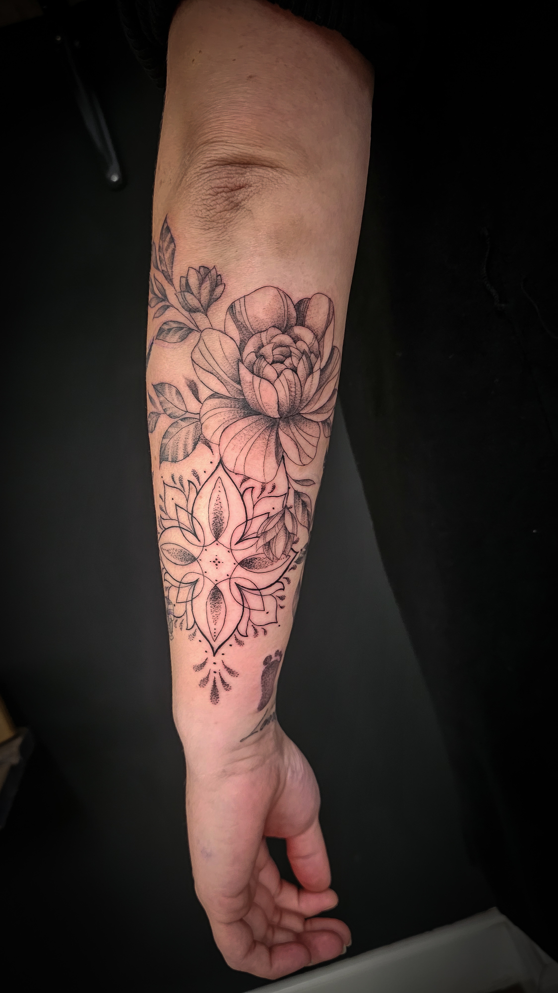 Fineline bloem en mandala op onderarm.