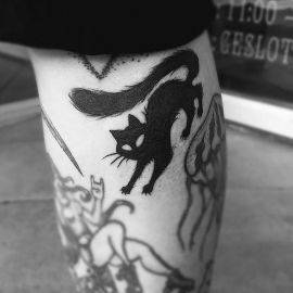 Zwarte silhouet tattoo van een kat met een borstelige staart op het onderbeen.