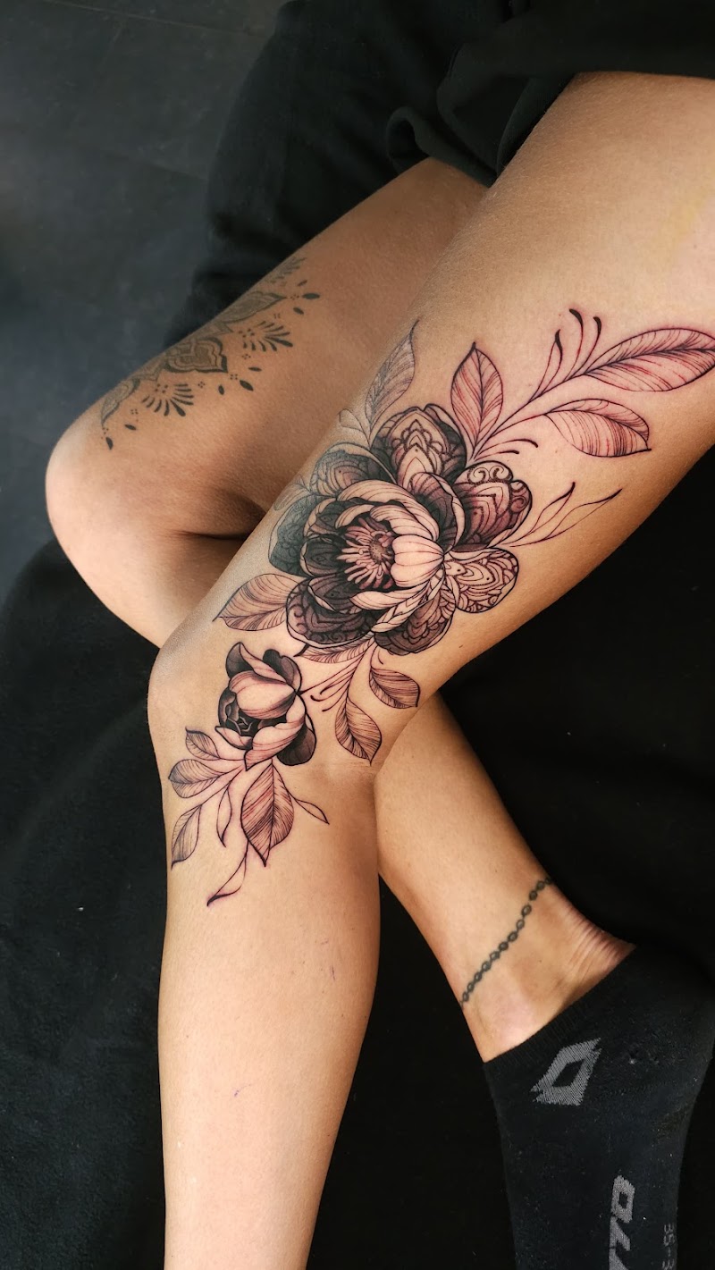 Grote bloemen tattoo op knie en bovenbeen, zwart-wit.