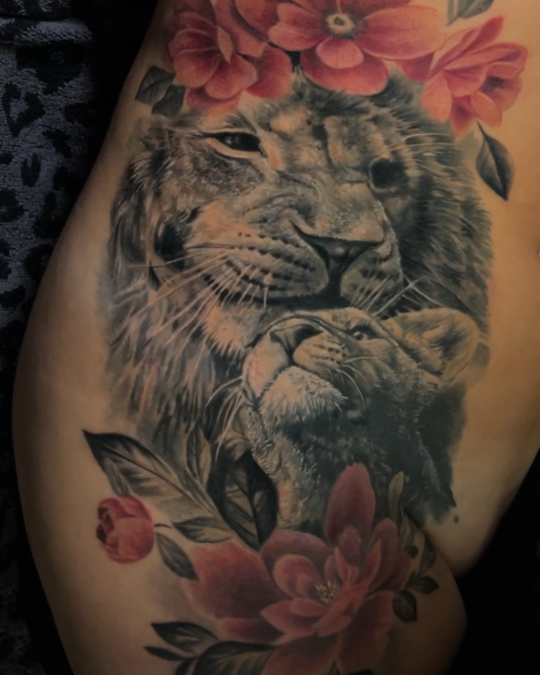 Realistische leeuw en welp met rode bloemen op de heup.