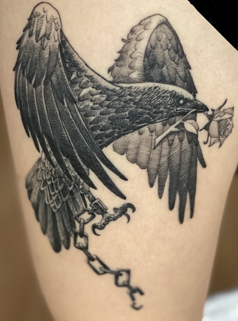 Zwart-wit tattoo van een raaf met een roos en een gebroken ketting.