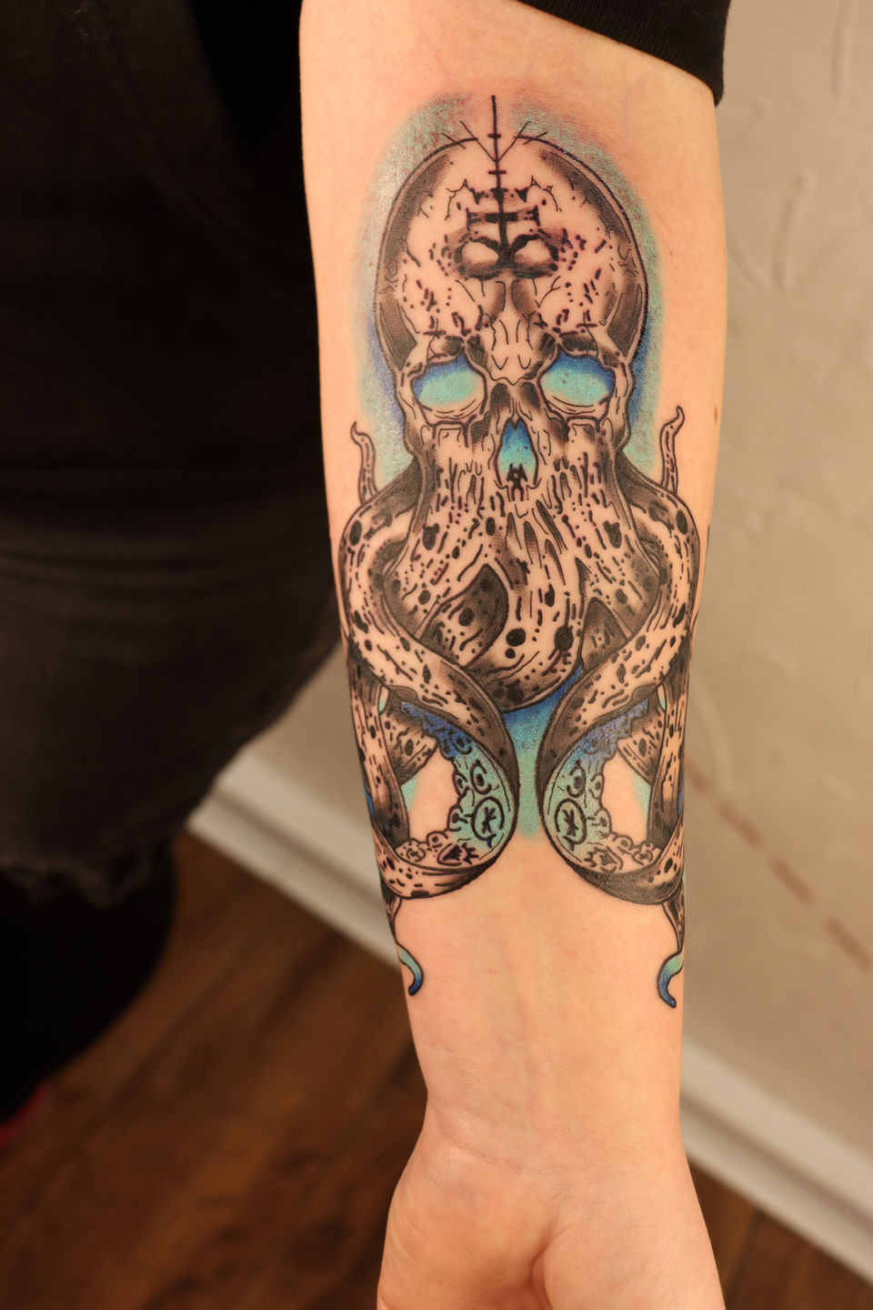 Schedel met octopustentakels en blauwe gloed op onderarm