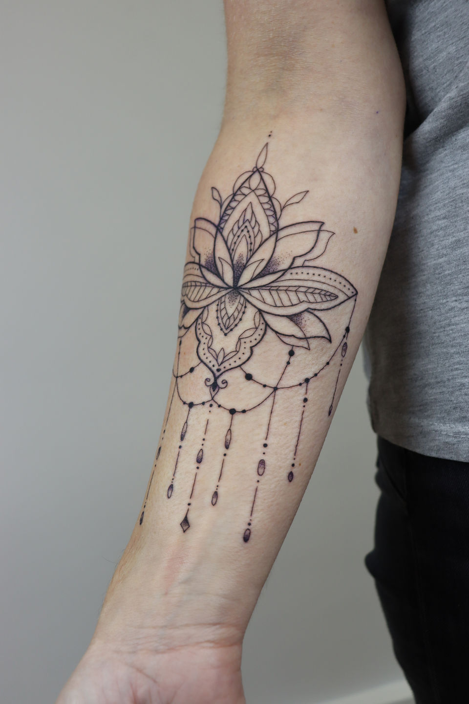 Blackwork lotus mandala met ornamenten op de onderarm.